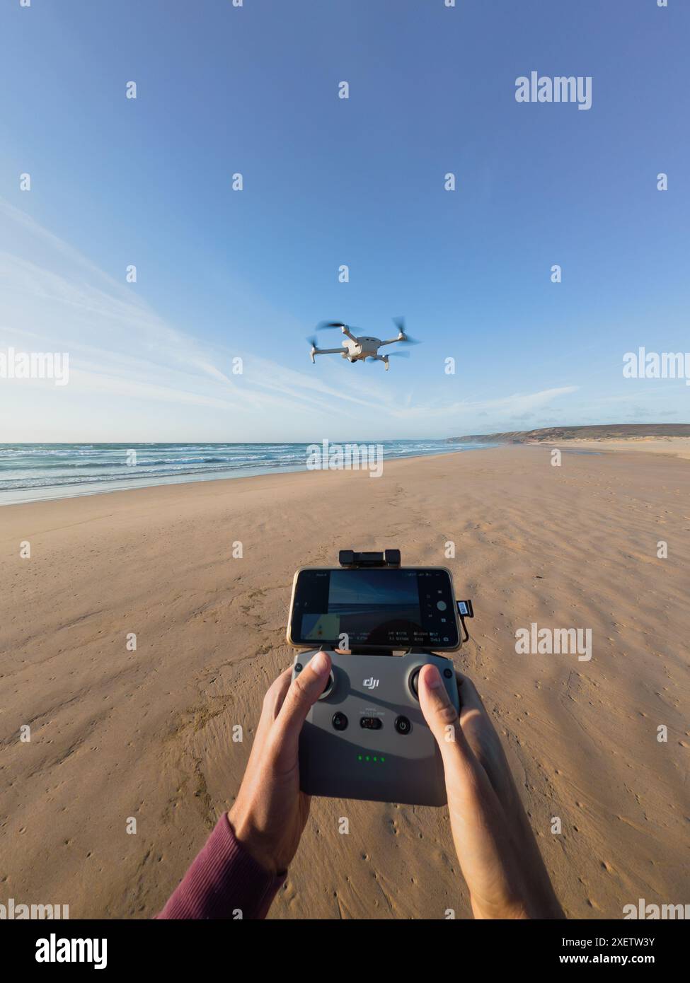 Praia da Bordeira, Portogallo: 25 giugno 2024: Pilotare un drone sulla spiaggia prospettiva personale Foto Stock