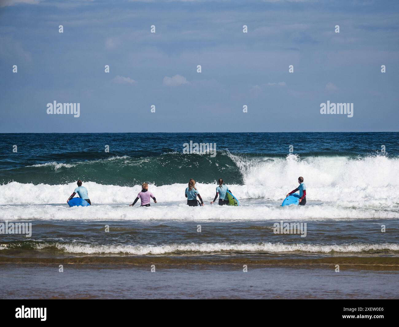 Praia da Bordeira, Portogallo; 26 giugno 2024: Studenti della scuola di surf che guardano un'onda di rottura a Praia da Bordeira, Algarve, Portogallo Foto Stock