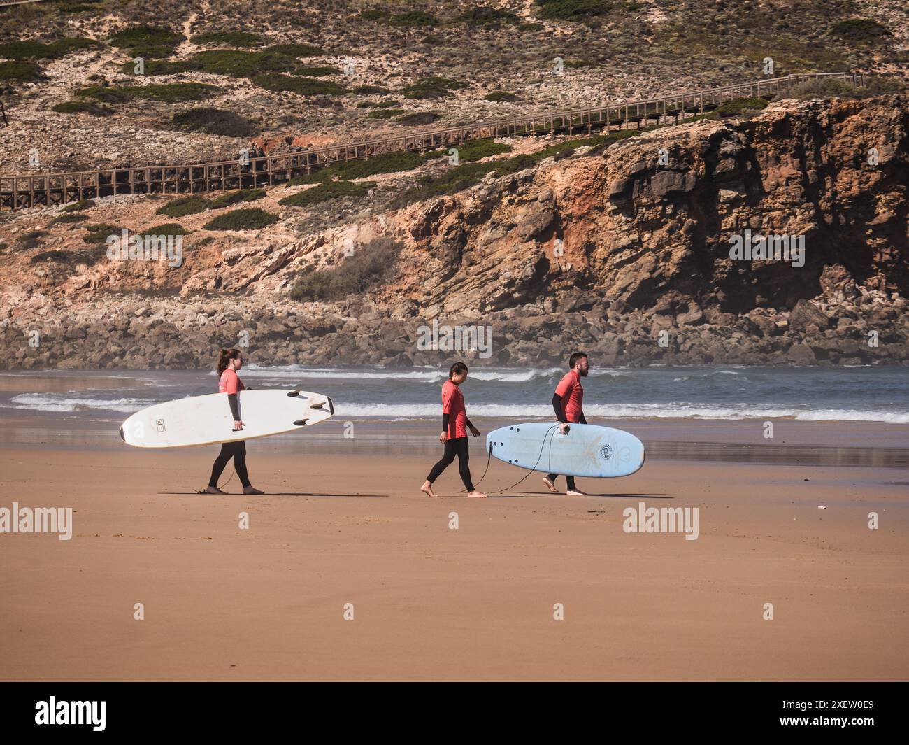 Praia da Bordeira, Portogallo; 26 giugno 2024: Studenti della scuola di surf che vanno in acqua con tavole da surf Foto Stock