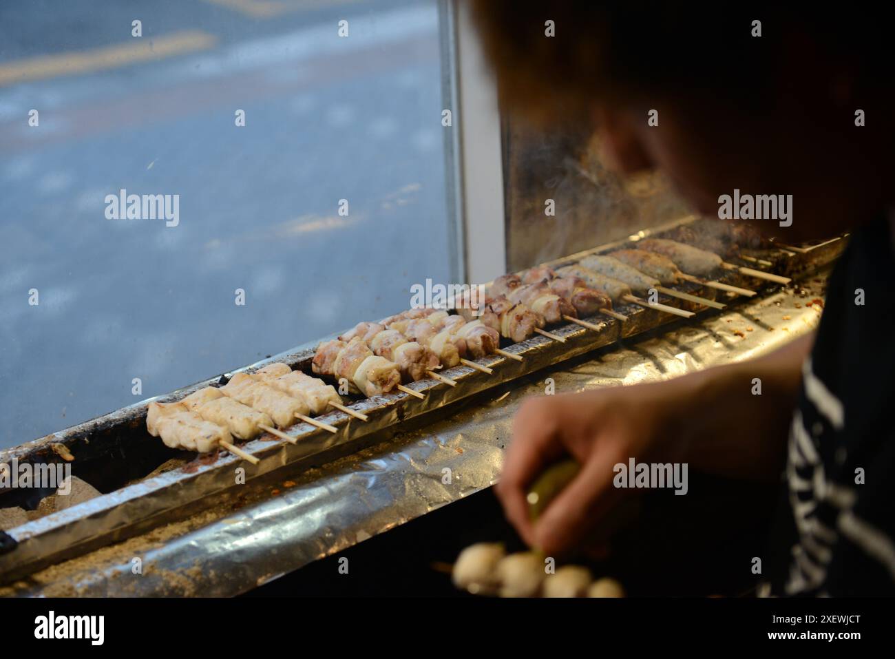 Un giovane giapponese che grigia spiedini al ristorante Washio Yakitori Izakaya a Chuocho, Kagoshima, Giappone. Foto Stock