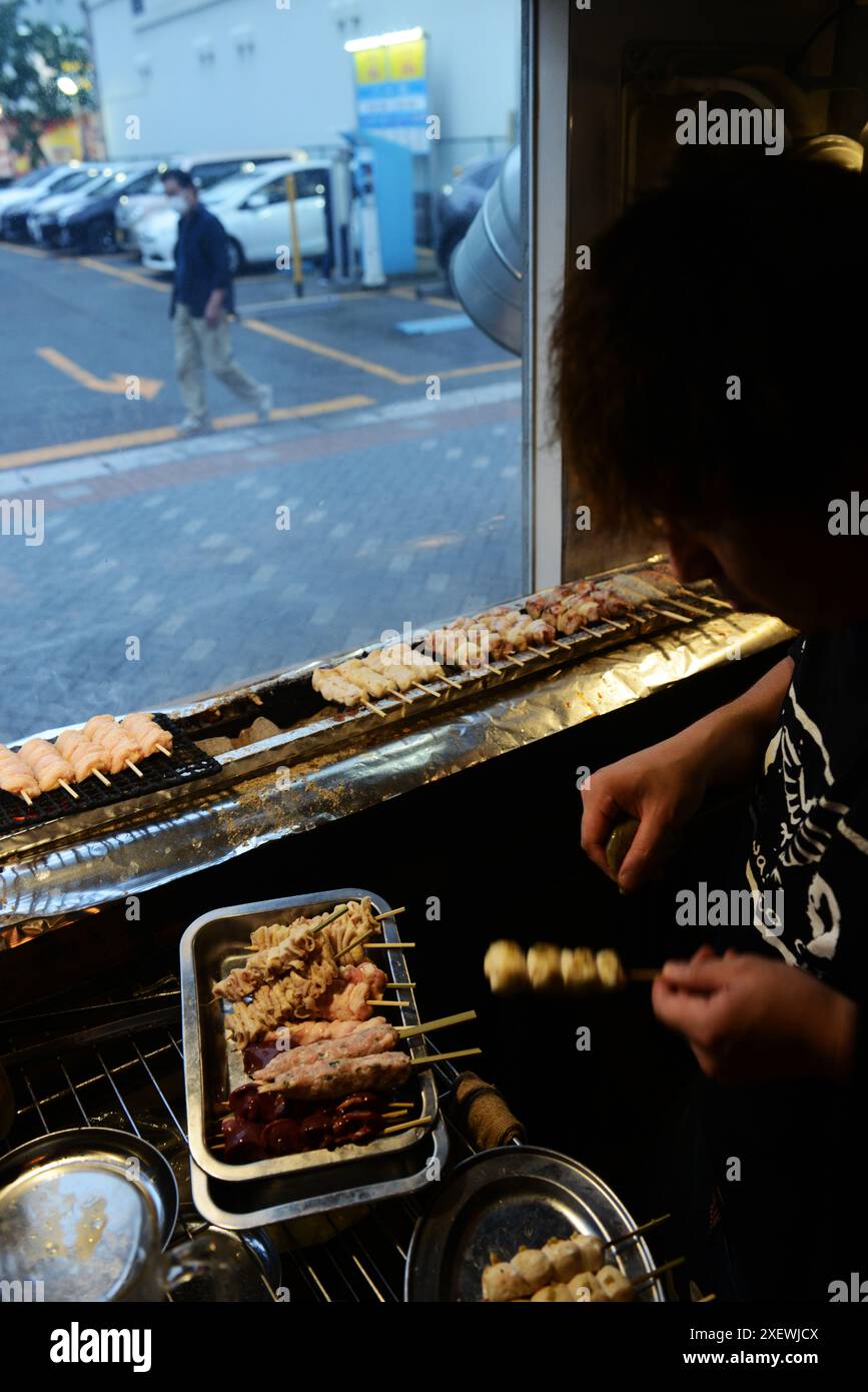 Un giovane giapponese che grigia spiedini al ristorante Washio Yakitori Izakaya a Chuocho, Kagoshima, Giappone. Foto Stock