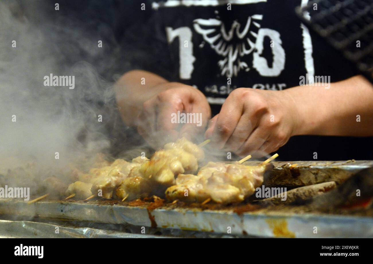 Un giovane giapponese che grigia spiedini al ristorante Washio Yakitori Izakaya a Chuocho, Kagoshima, Giappone. Foto Stock