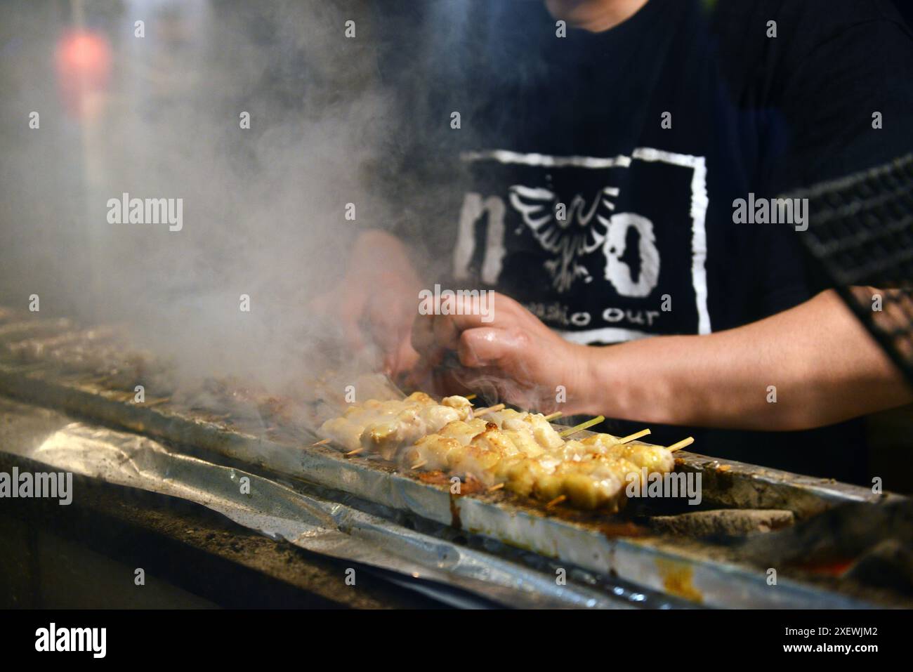 Un giovane giapponese che grigia spiedini al ristorante Washio Yakitori Izakaya a Chuocho, Kagoshima, Giappone. Foto Stock