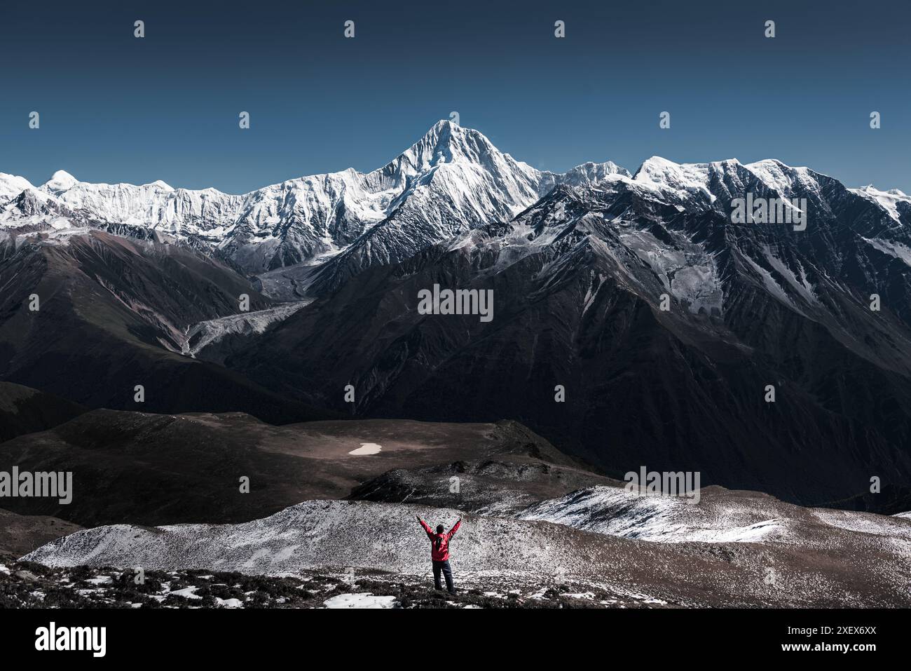 Un escursionista in piedi su una terra con sfondo il Monte Gongga, che è la vetta più alta della provincia di Sichuan, in Cina. Foto Stock