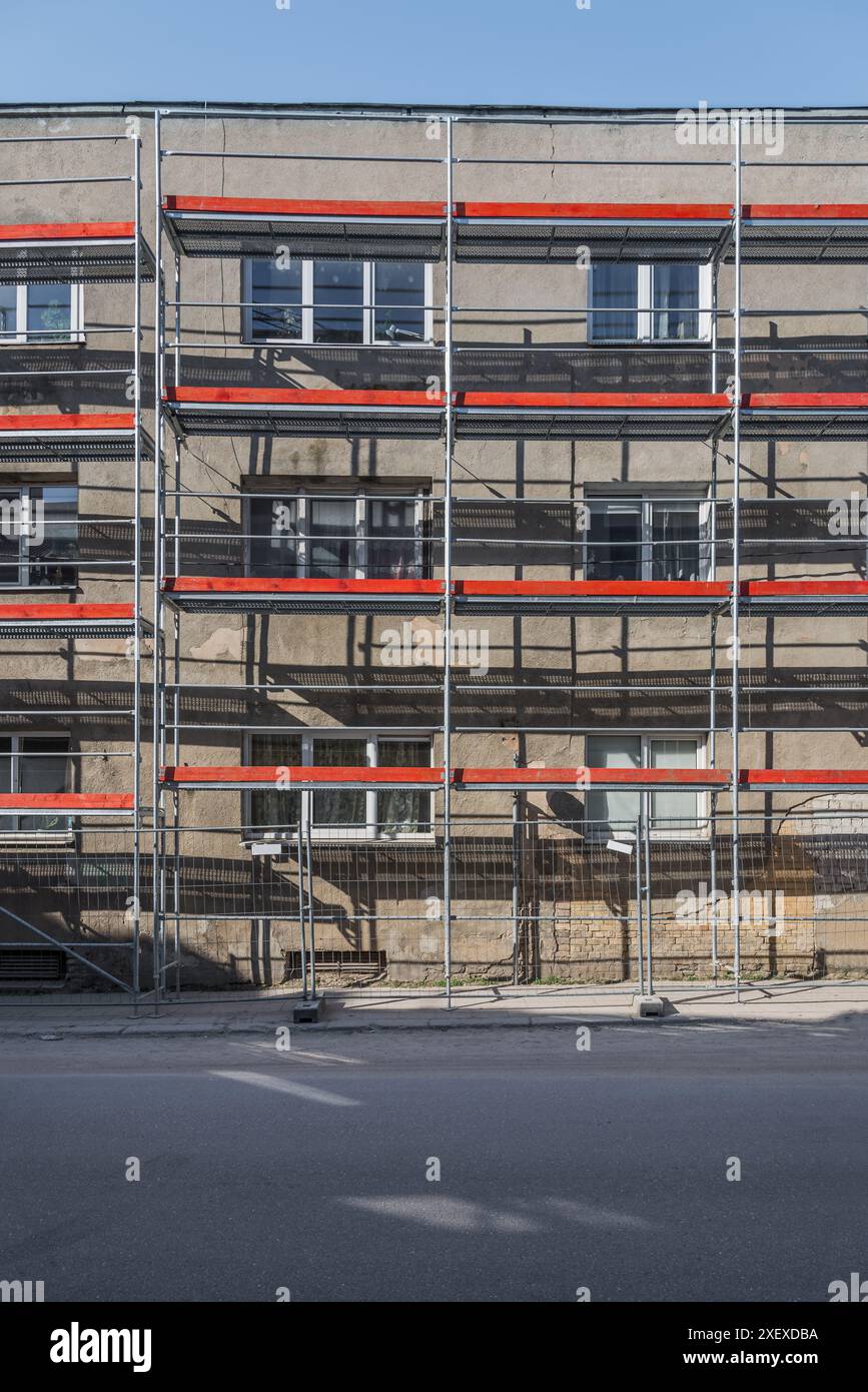 Vecchio edificio residenziale ristrutturato con impalcature nella strada vuota Foto Stock