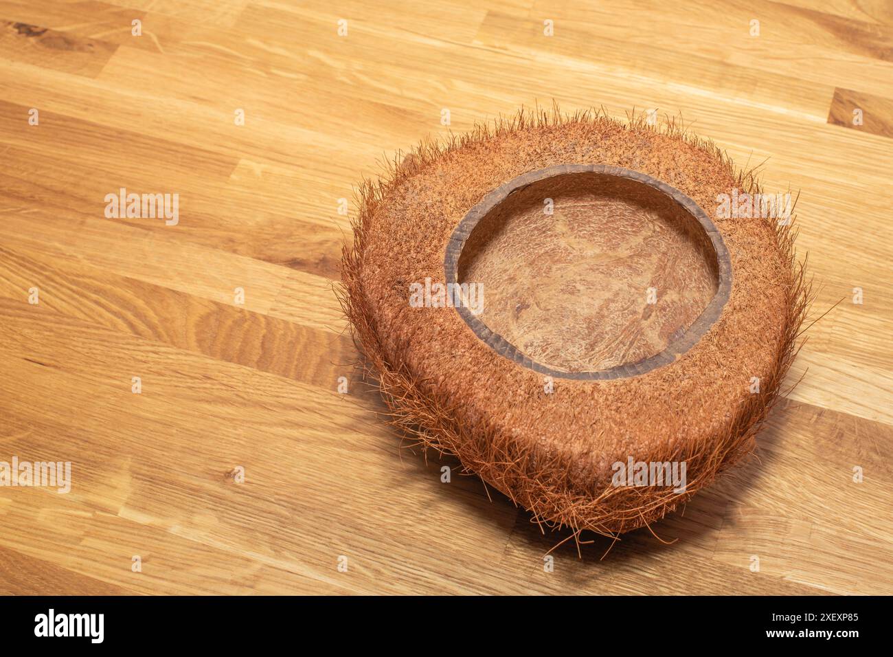 Ciotola pelosa di cocco naturale o vaso di fiori su un tavolo in legno di quercia. Guscio di cocco Foto Stock