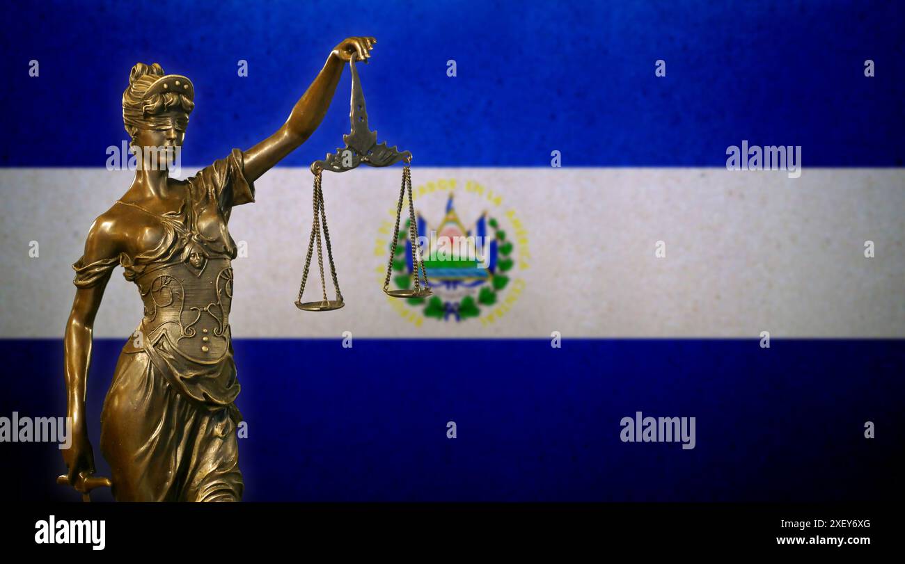 Primo piano di una piccola statuetta di bronzo di Lady Justice davanti a una bandiera di El Salvador. Foto Stock