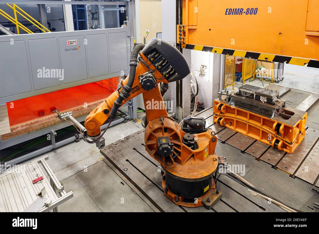 Robot che introduce i materiali nel forno e li porta successivamente alla pressa, alla cella di stampaggio a caldo, all'unità industriale, all'industria automobilistica, al centro tecnologico Foto Stock