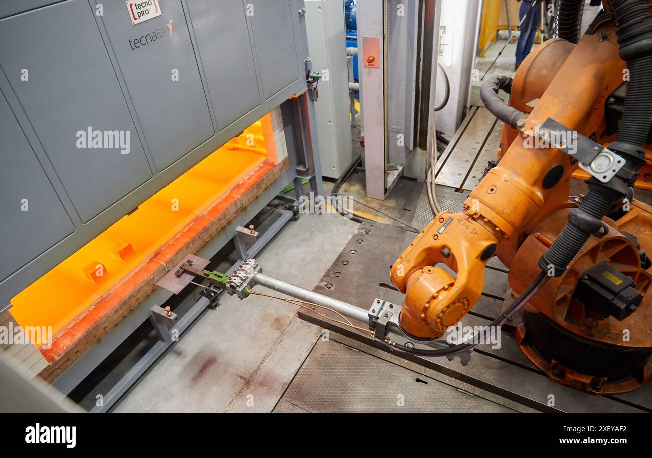 Robot che introduce i materiali nel forno e li porta successivamente alla pressa, alla cella di stampaggio a caldo, all'unità industriale, all'industria automobilistica, al centro tecnologico Foto Stock