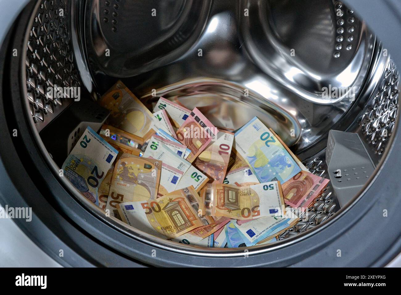 RICICLAGGIO DI DENARO - CRIMINALITÀ - FINANZA - EURO. Banconote in euro in lavatrice Foto Stock
