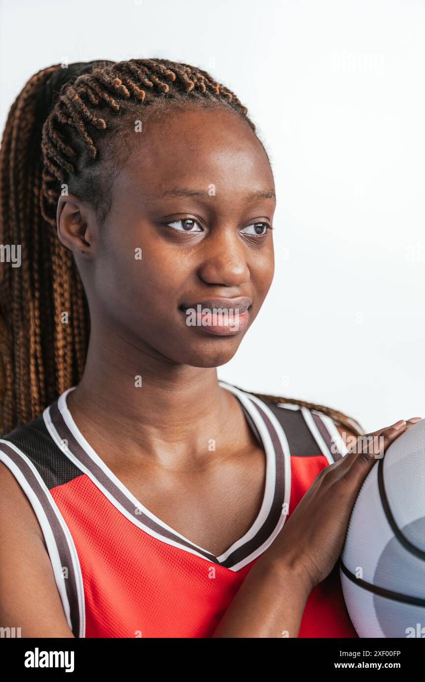 Foto in primo piano verticale di una determinata giocatrice di basket che regge un pallacanestro e indossa una maglia rossa. L'immagine evidenzia la messa a fuoco e la lettura Foto Stock