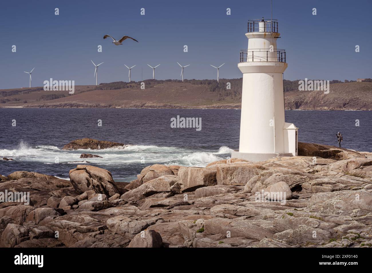 Tranquillità costiera: Faro di Muxia e turbine eoliche (Galizia, Spagna) Foto Stock