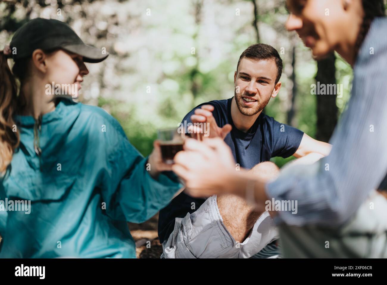 Gruppo di amici che si godono un drink nella foresta in una giornata di sole Foto Stock