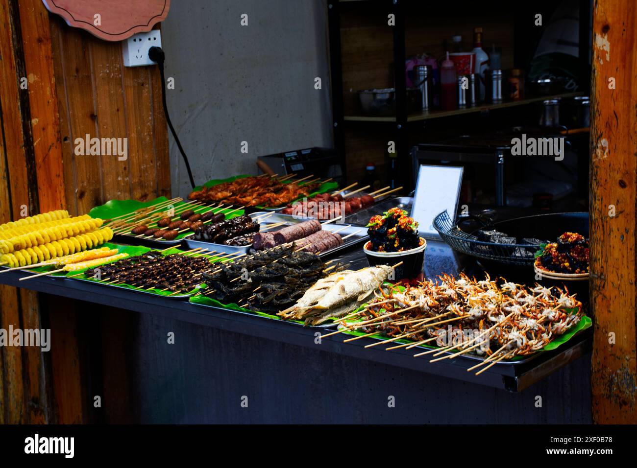 Piatti tradizionali cinesi, pasti gourmet o cucina locale, spiedini di pesce a base di tribù culturale per i viaggiatori che assaggiano le bevande al ristorante Xiang Foto Stock