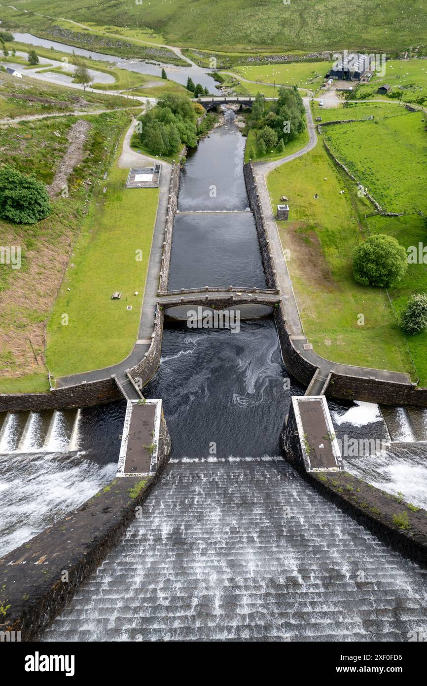 Diga di Claerwen nella valle di Elan, con acqua che scorre sopra la cima. L'acqua immagazzinata qui fornisce la città inglese di Birmingham. Powys, Regno Unito. Foto Stock