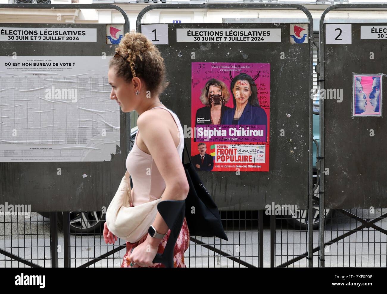 Parigi, Francia. 30 giugno 2024. Una donna passa davanti a un manifesto della campagna elettorale della nuova alleanza di sinistra, Nouveau Front Populaire NFP (nuovo fronte Popolare), di fronte a una postazione elettorale durante il primo turno delle elezioni parlamentari a Parigi, in Francia, domenica 30 giugno 2024. I sondaggi suggeriscono che il Presidente francese Emmanuel Macron si troverà di fronte a un parlamento ostile, dominato da due blocchi radicali, l'estrema destra e l'estrema sinistra. Foto di Maya Vidon-White/UPI credito: UPI/Alamy Live News Foto Stock