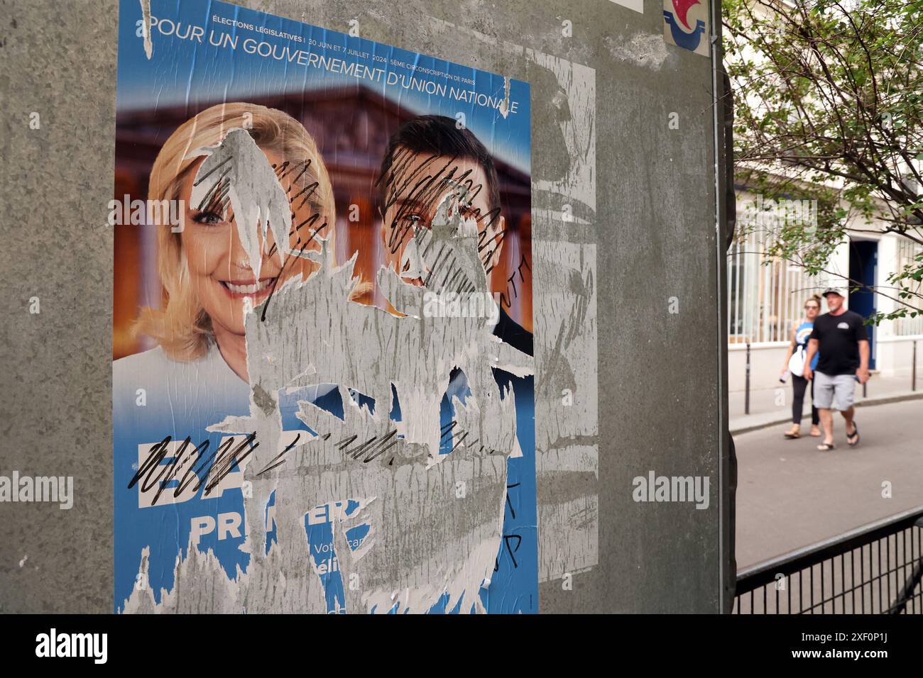 Parigi, Francia. 30 giugno 2024. Un deturpato manifesto della campagna del Rassemblement National di estrema destra (Rally Nazionale), mostra il leader del partito Marine le Pen (L) e il suo protetto di 28 anni, Jordan Bardella, di fronte a una stazione elettorale durante il primo turno delle elezioni parlamentari a Parigi, in Francia, domenica 30 giugno 2024. Il paese diviso sta votando in elezioni anticipate ad alta quota che potrebbero vedere il partito di estrema destra impadronirsi del potere in una prima storica. Foto di Maya Vidon-White/UPI credito: UPI/Alamy Live News Foto Stock