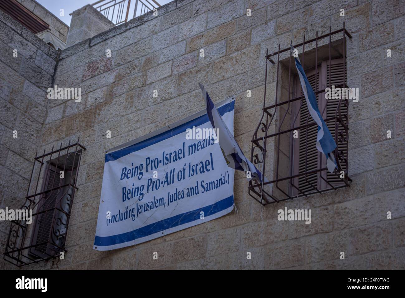 La bandiera politica israeliana dice: "Essere pro-Israele significa essere pro-tutti di Israele (compresi Gerusalemme, Giudea e Samaria!)” Sul muro di Gerusalemme. Foto Stock