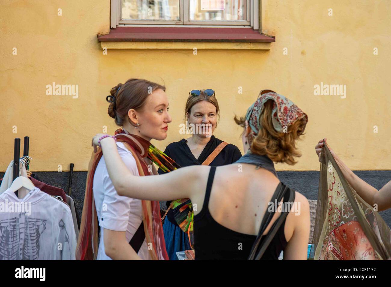 Giovani donne che provano abiti o accessori di seconda mano per la taglia al sisäpihat mercato delle pulci pop-up Vallila di Helsinki, in Finlandia Foto Stock