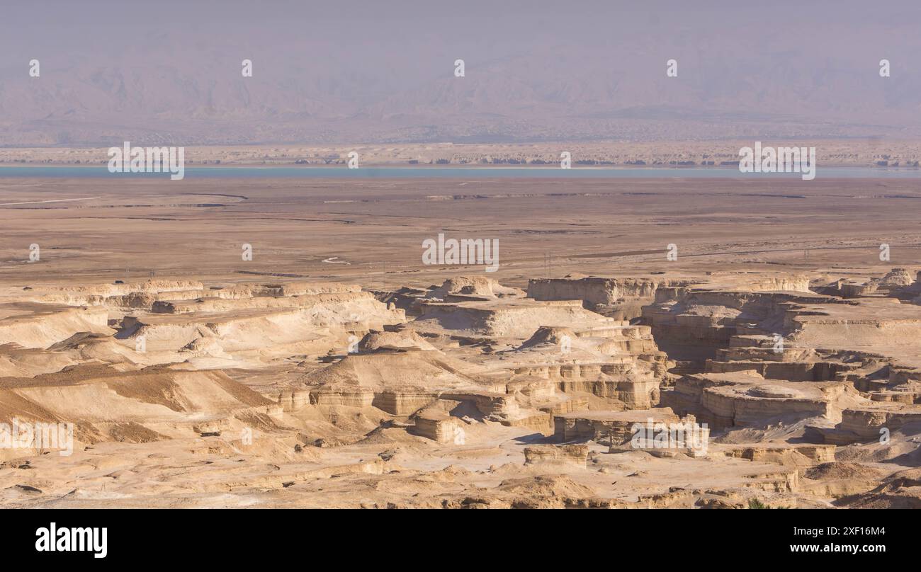 Le rocce del deserto sulla costa del Mar morto in Israele, con il deserto della Giudea e il confine con la Giordania sullo sfondo. Foto Stock