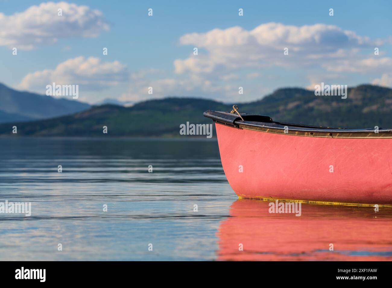 Vista estiva nel nord del Canada con vista sul lago e sulle montagne. Canoa rossa in vista a fuoco. Foto Stock