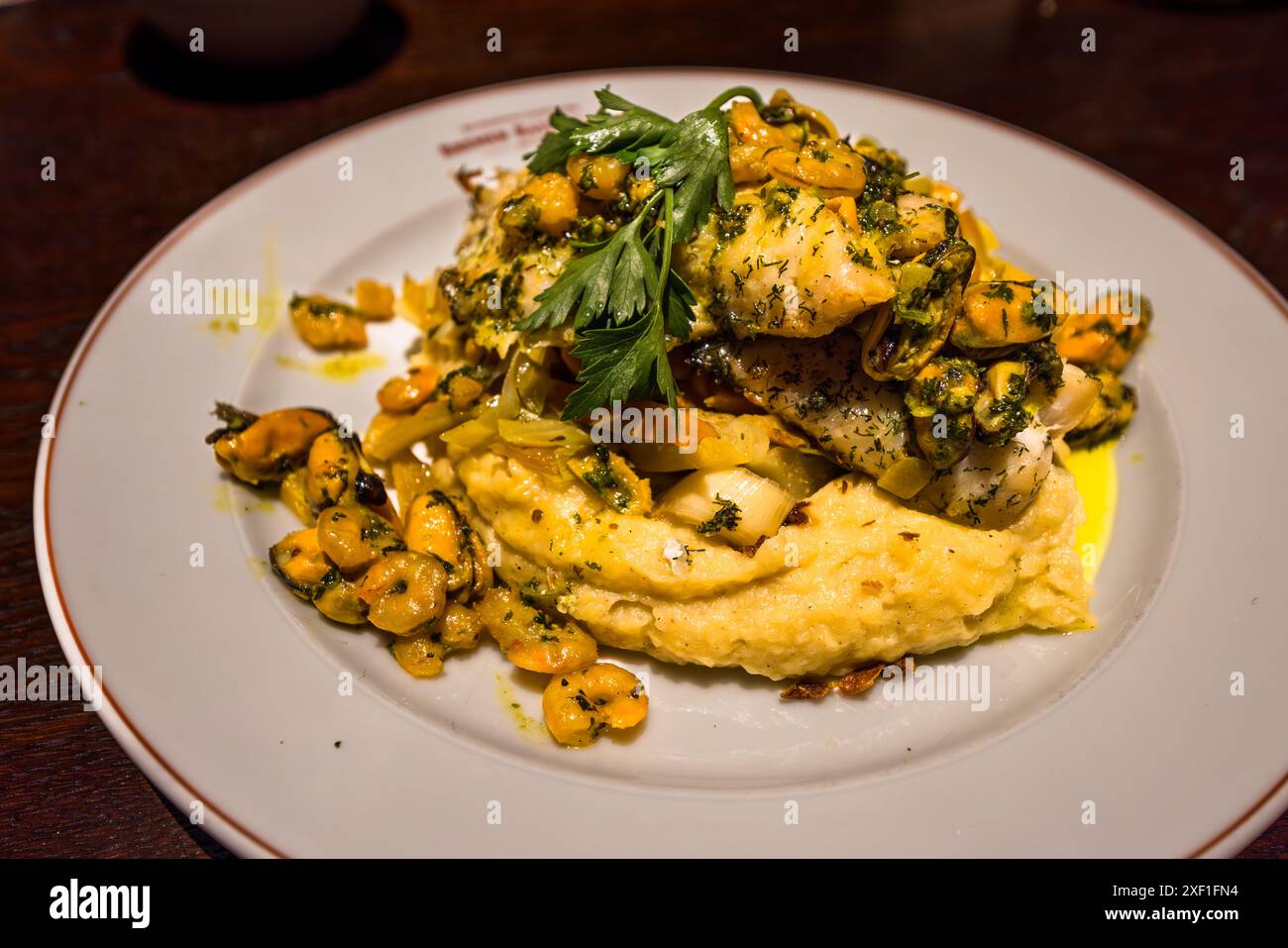 Filetto di pesce rosso fritto con cozze e gamberetti nel burro alle erbe su un purè di patate e cipolle arrostite con ortaggi a radice, un piatto sostanzioso del Ratskeller di Brema. Brema, Germania. Foto Stock