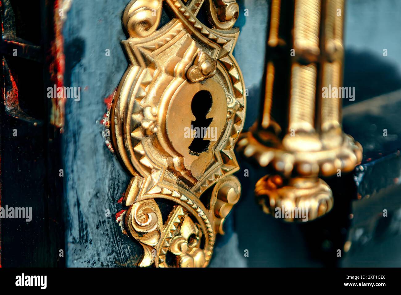 Porta in legno con pomello e maniglia dorati lucidi. La figura mostra una chiave dorata con un foro per chiavetta. Concetto di mistero e intrigo Foto Stock