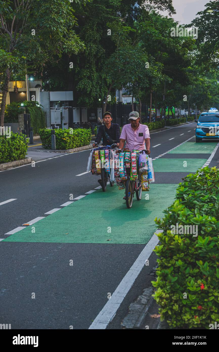 Giacarta, Indonesia - 10 maggio 2024. i giovani e i vecchi venditori di caffè in bicicletta stanno andando alle loro destinazioni di vendita. Foto Stock