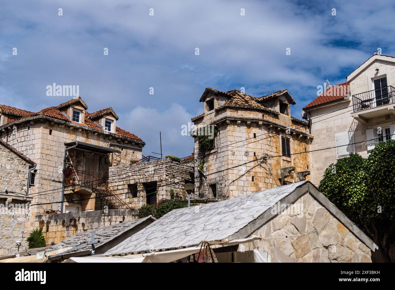 Case tradizionali in pietra con tetti di tegole sotto un cielo blu nuvoloso Supetar, isola di Brac, Croazia Foto Stock