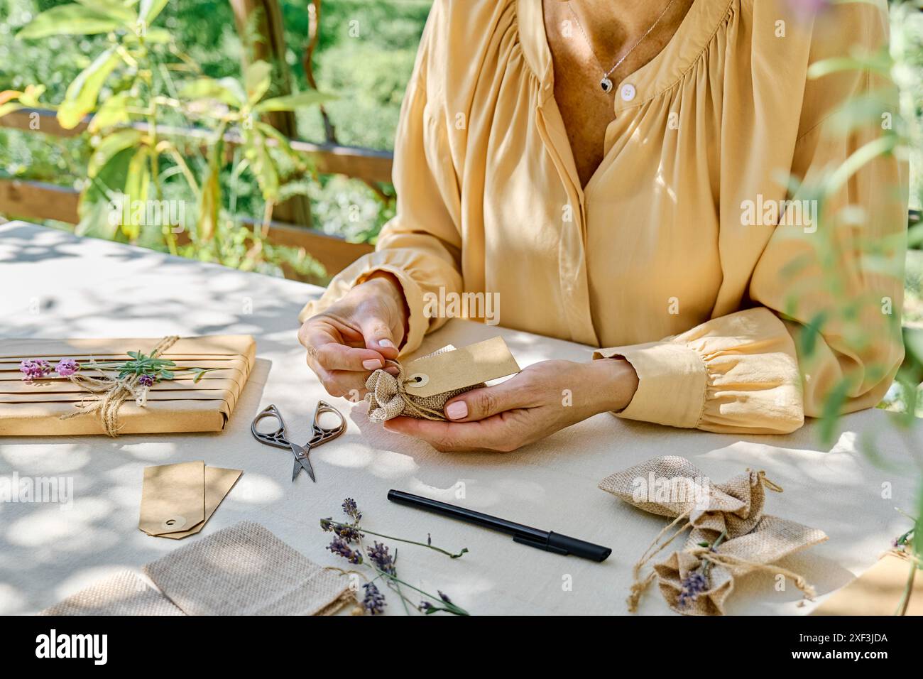 Donna che produce bustina di lavanda, piccola borsa per odorare i vestiti e metterli nel guardaroba. Regalo fai da te senza sprechi. Aromaterapia fatta in casa. Foto Stock