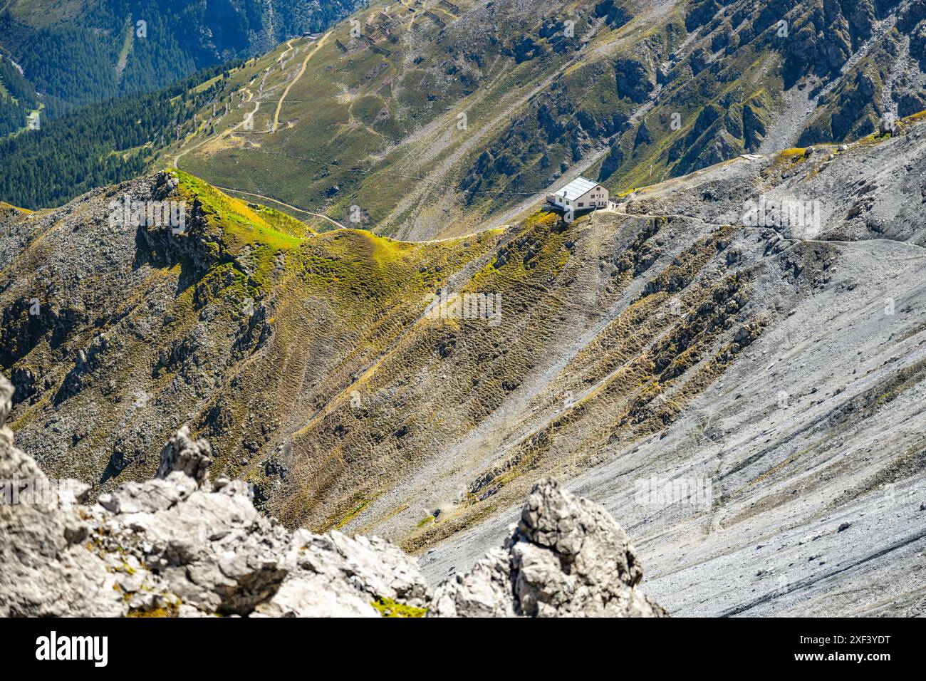 Il Rifugio Tabaretta si trova su un'aspra cresta sullo sfondo delle montagne di Ortles, pendii suggestivi e vegetazione alpina in estate. Foto Stock