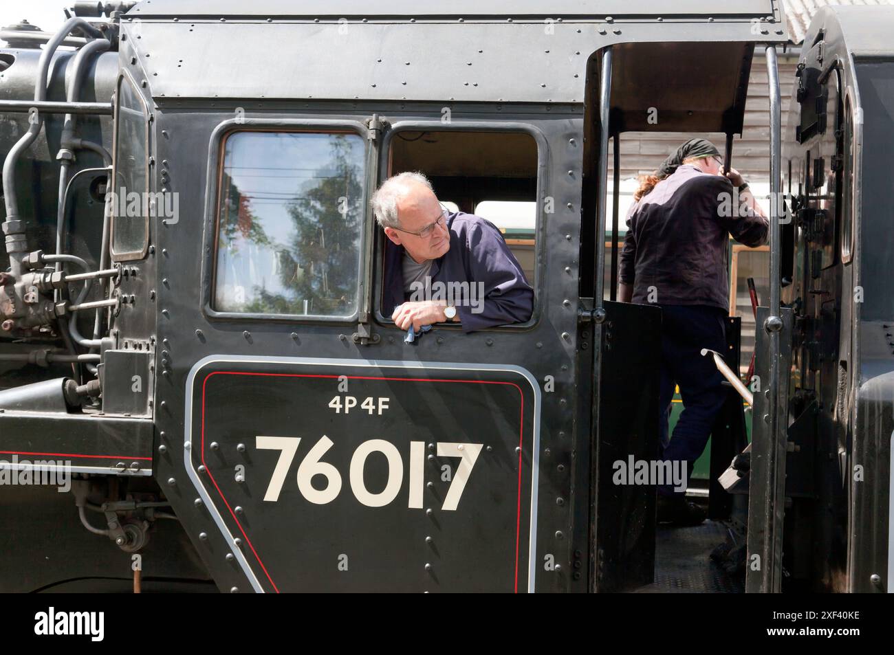 Primo piano dell'autista e del pompiere sulla pedana del pullman Wealden, locomotiva n. 76017, che sale in retromarcia fino al treno, alla stazione di Tenterden Town, Foto Stock