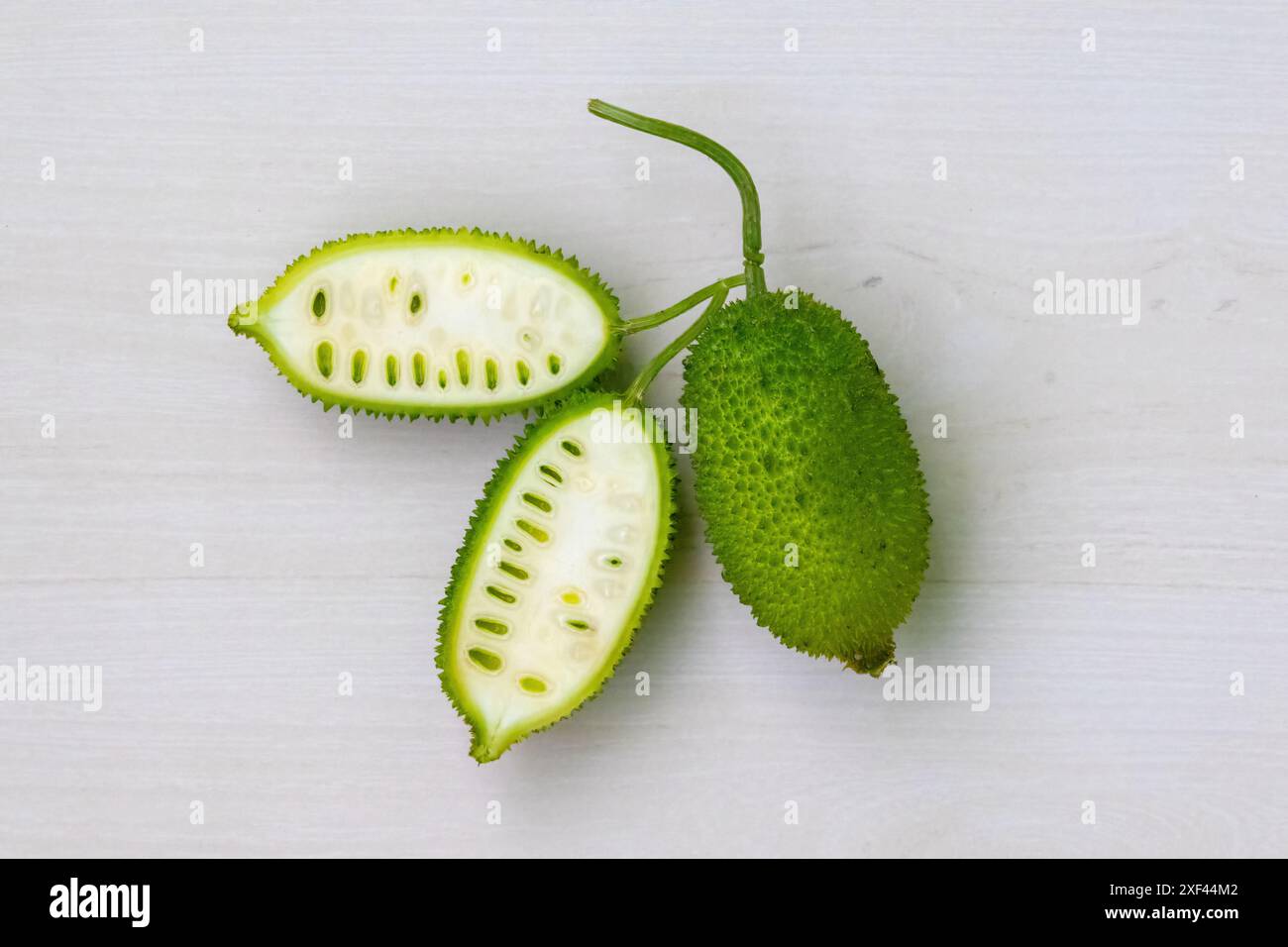 Verdure verdura di gnocchia spinosa a fette su sfondo bianco chiaro di legno. Momordica dioica è anche conosciuta come Kakrol, Kartoli, Kankoda, Kantola. Foto Stock