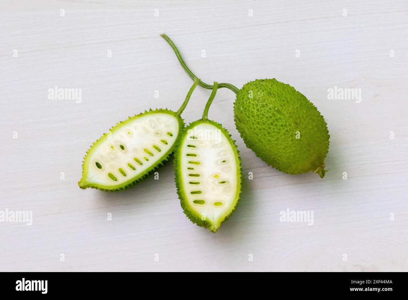 Verdure verdura di gnocchia spinosa a fette su sfondo bianco chiaro di legno. Momordica dioica è anche conosciuta come Kakrol, Kartoli, Kankoda, Kantola. Foto Stock