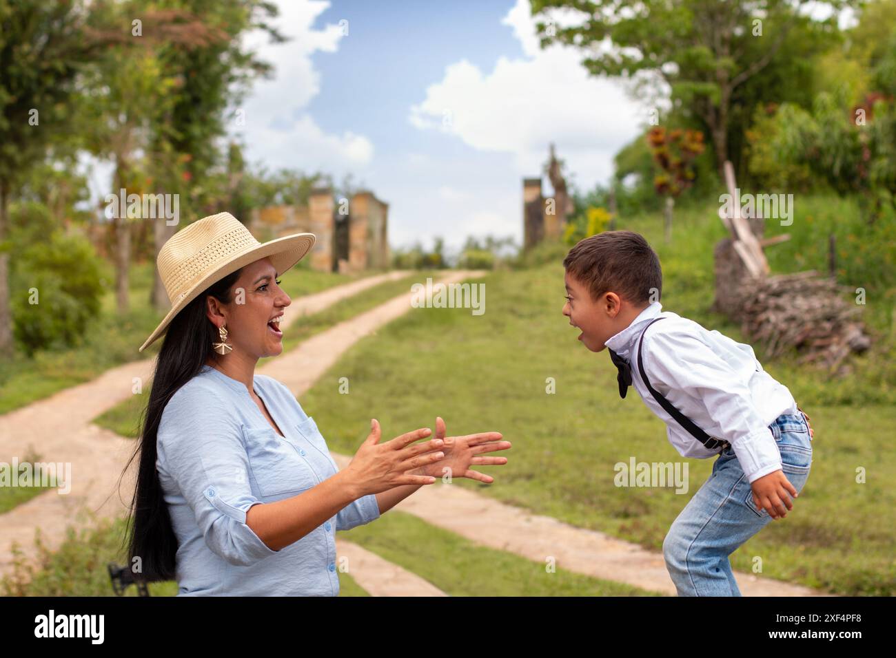 stile di vita: madre e figlio con sindrome di down all'aperto giocano per sorprendersi a vicenda Foto Stock