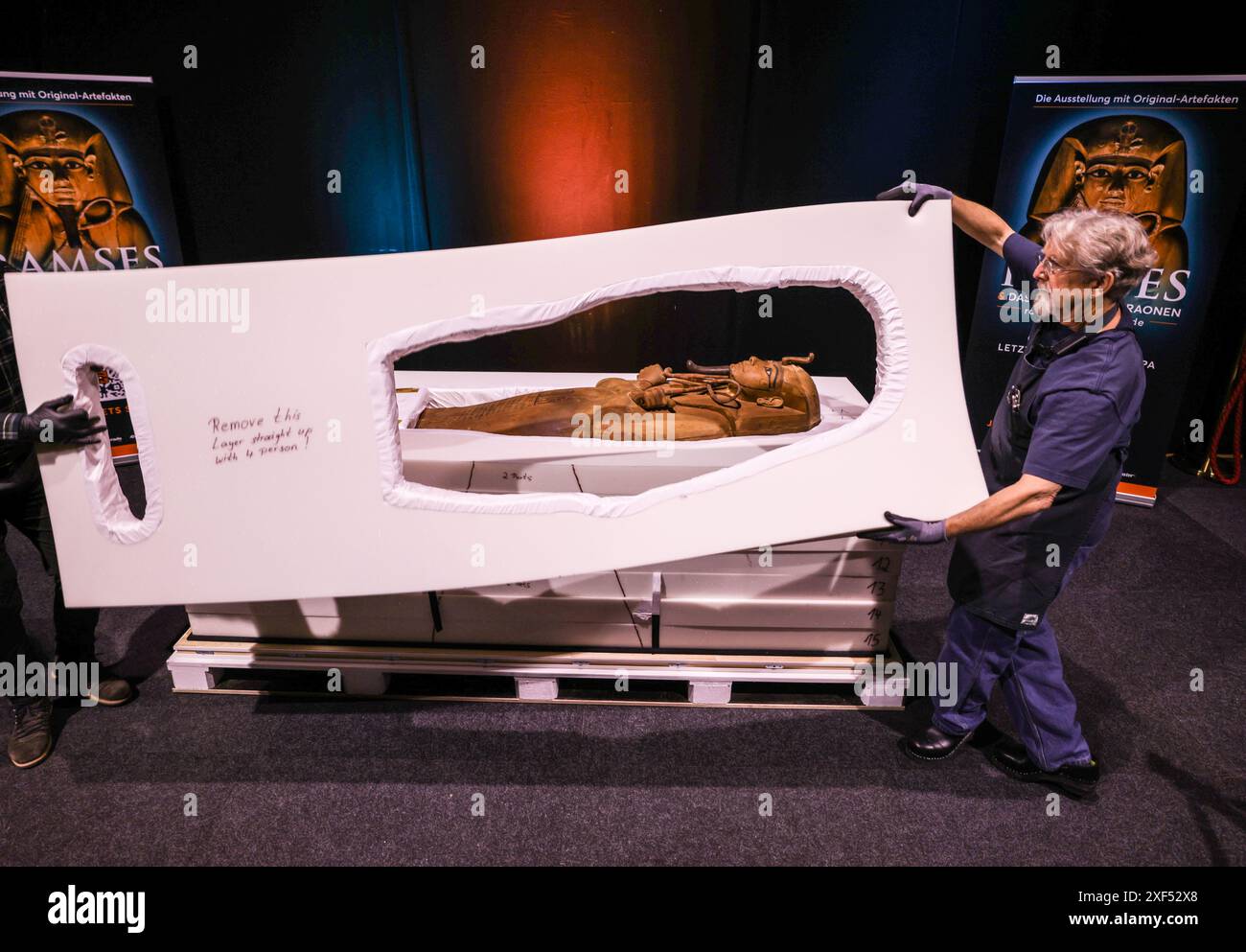 01 luglio 2024, Colonia;: Lo staff dell'Odysseum Museum di Colonia decomprime il sarcofago del faraone Ramses II per la mostra "Ramses and the Gold of the Pharaohs", che viene presentata per la prima volta in Germania. L'oggetto centrale è il sarcofago di Ramsete II, scoperto nel 1811 in una tomba durante uno scavo archeologico sulla riva occidentale del Nilo. Foto: Oliver Berg/dpa Foto Stock
