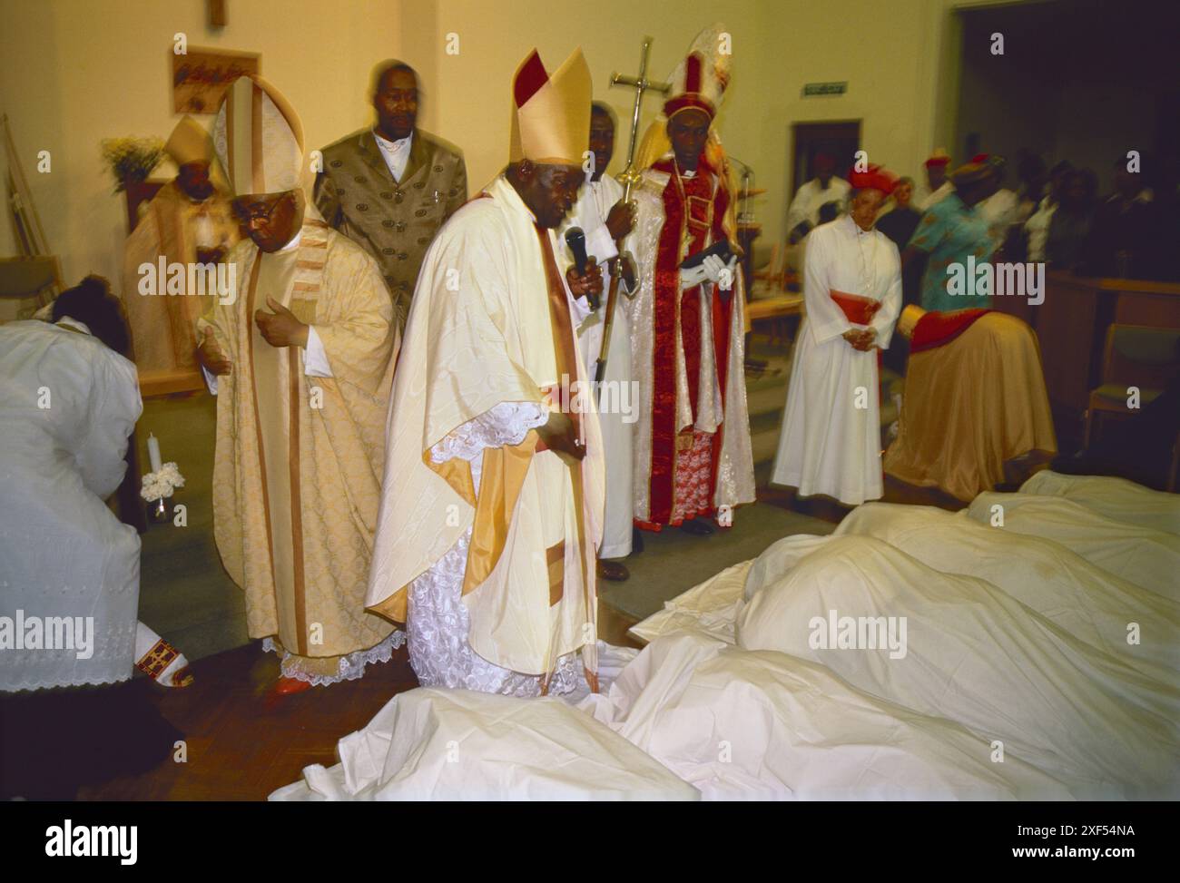 Prostrate religione, in adorazione e sottomissione davanti al nuovo Vescovo e al Signore Gesù. La Chiesa albezia, 'basata sui principi di Cristo', i membri della congregazione si prostrano e sono coperti da un foglio bianco, il Vescovo li benedice come parte del servizio ecclesiastico durante l'incoronazione del Vescovo Barrington Young. Harlesden, Londra, Inghilterra intorno agli anni '1995 1990 UK HOMER SYKES Foto Stock