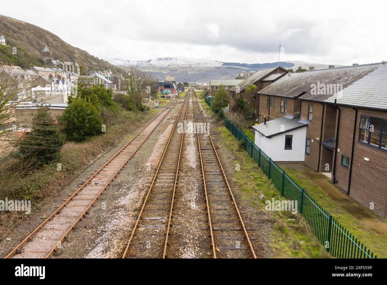 La Cambrian Coast Line che attraversa Barmouth, con falchi ricoperti di neve sullo sfondo. Galles del Nord Regno Unito. Marzo 2024 Foto Stock