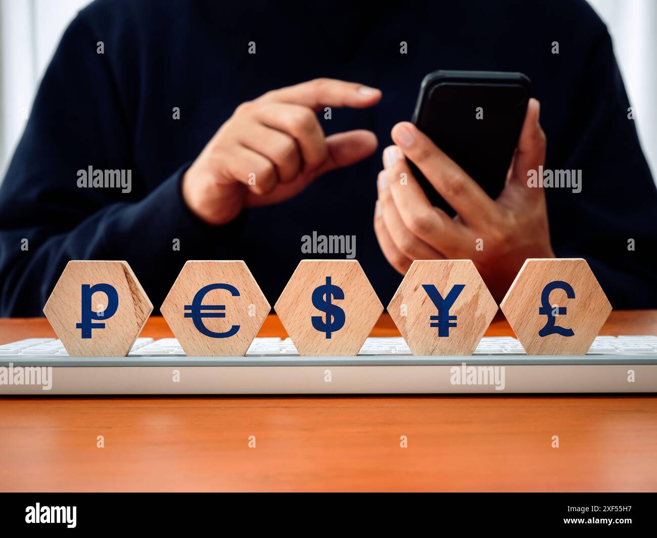 Cambio di denaro, convertitore di valuta estera, app online e concetto di pagamento interbancario. Icone delle valute su blocco di legno mentre il lavoratore CA Foto Stock