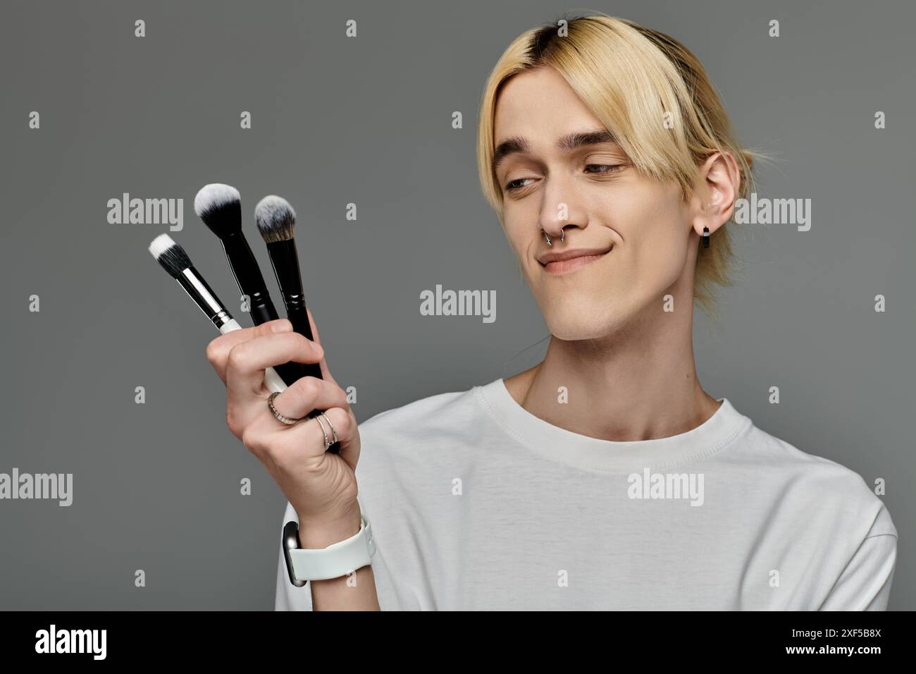 L'uomo regge graziosamente un mucchio di pennelli per il trucco. Foto Stock