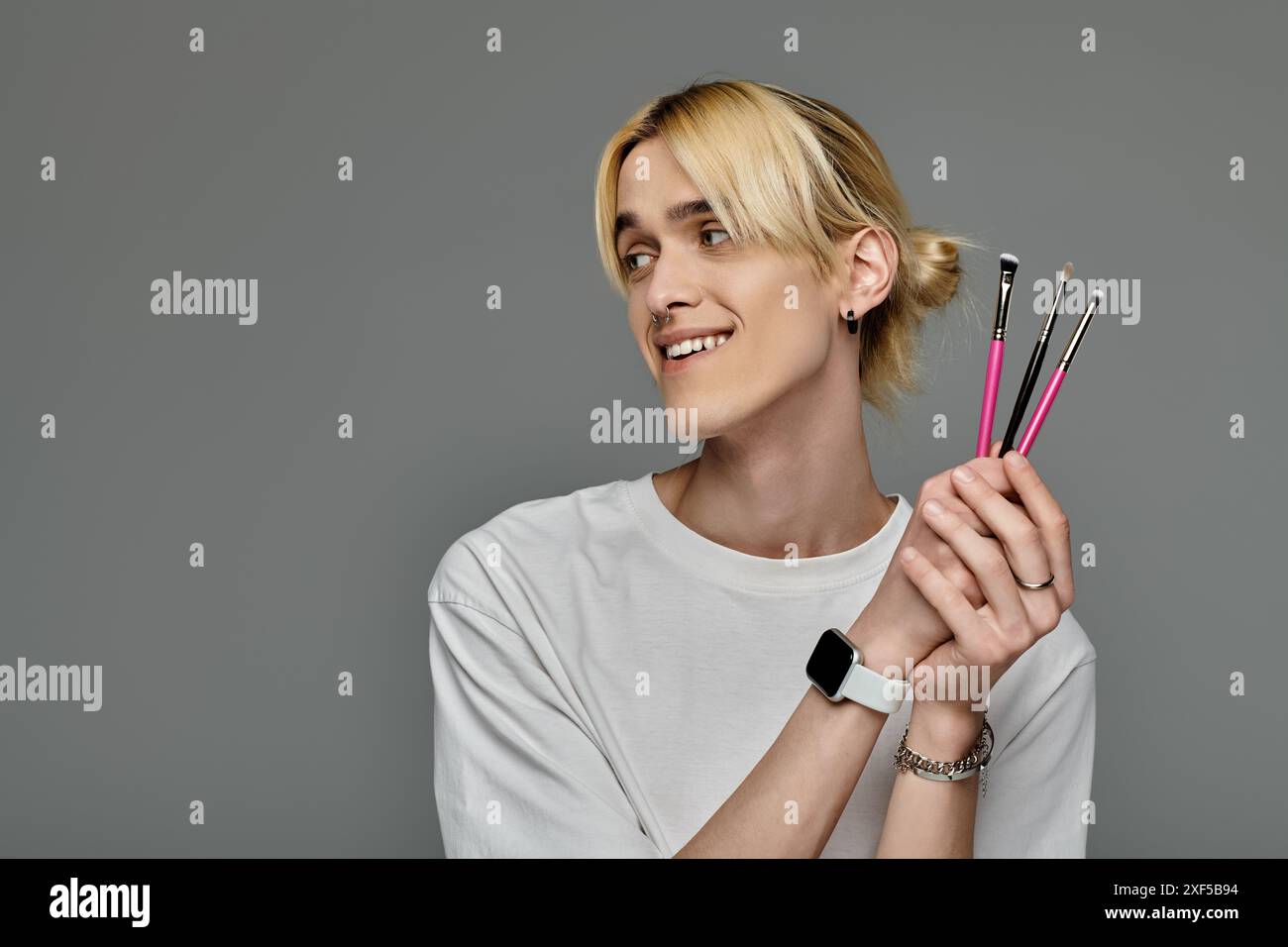 Bell'uomo in un abito alla moda che regge pennelli per il trucco. Foto Stock