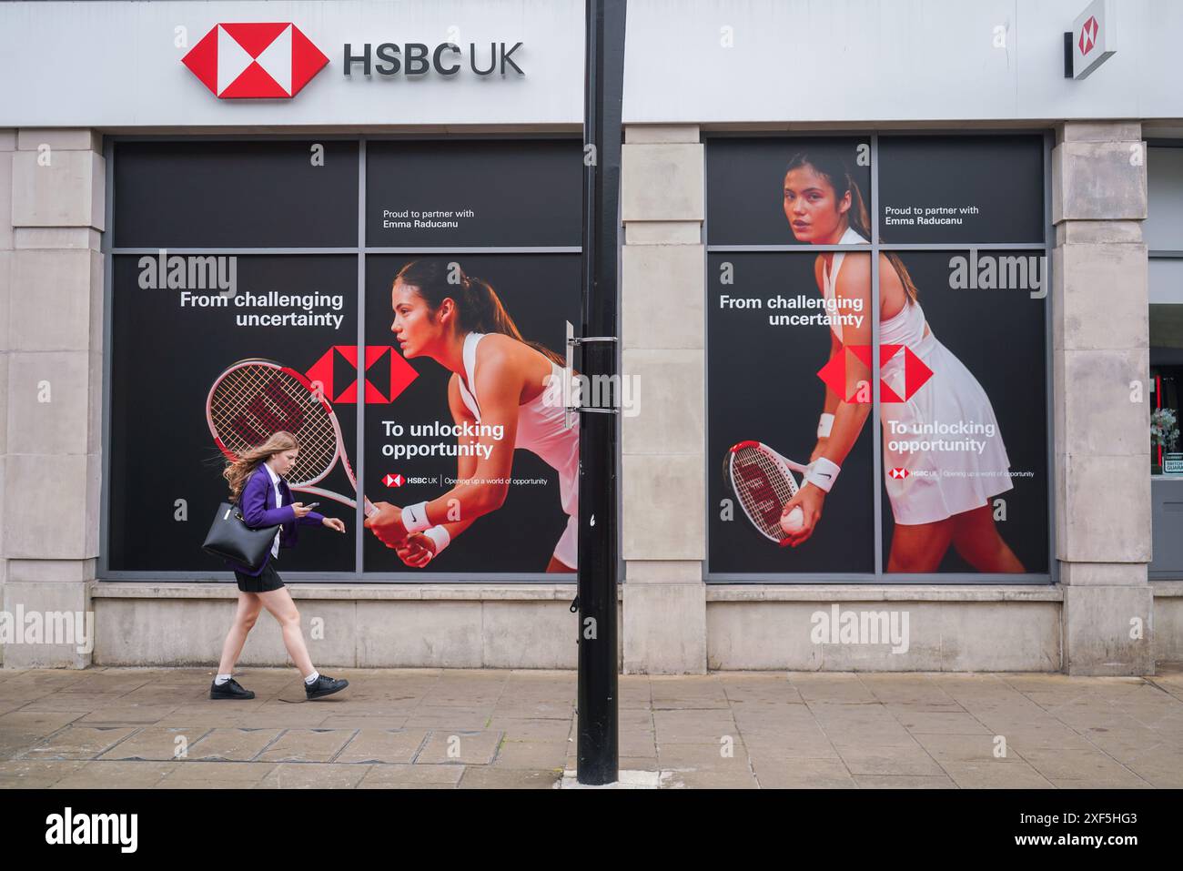 Wimbledon, Londra, Regno Unito 1° luglio 2024. Un'area pedonale passeggia accanto a una filiale locale della banca HSBC nel centro della città di Wimbledon. Con una foto della tennista britannica Emma Raducanu come ambasciatrice del marchio globale. Crediti: Amer Ghazzal/Alamy Live News Foto Stock