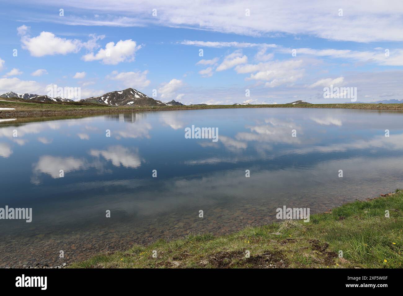 Vista di un bacino idrico sulla Wildkogel Arena, le cui acque blu riflettono nuvole bianche Foto Stock