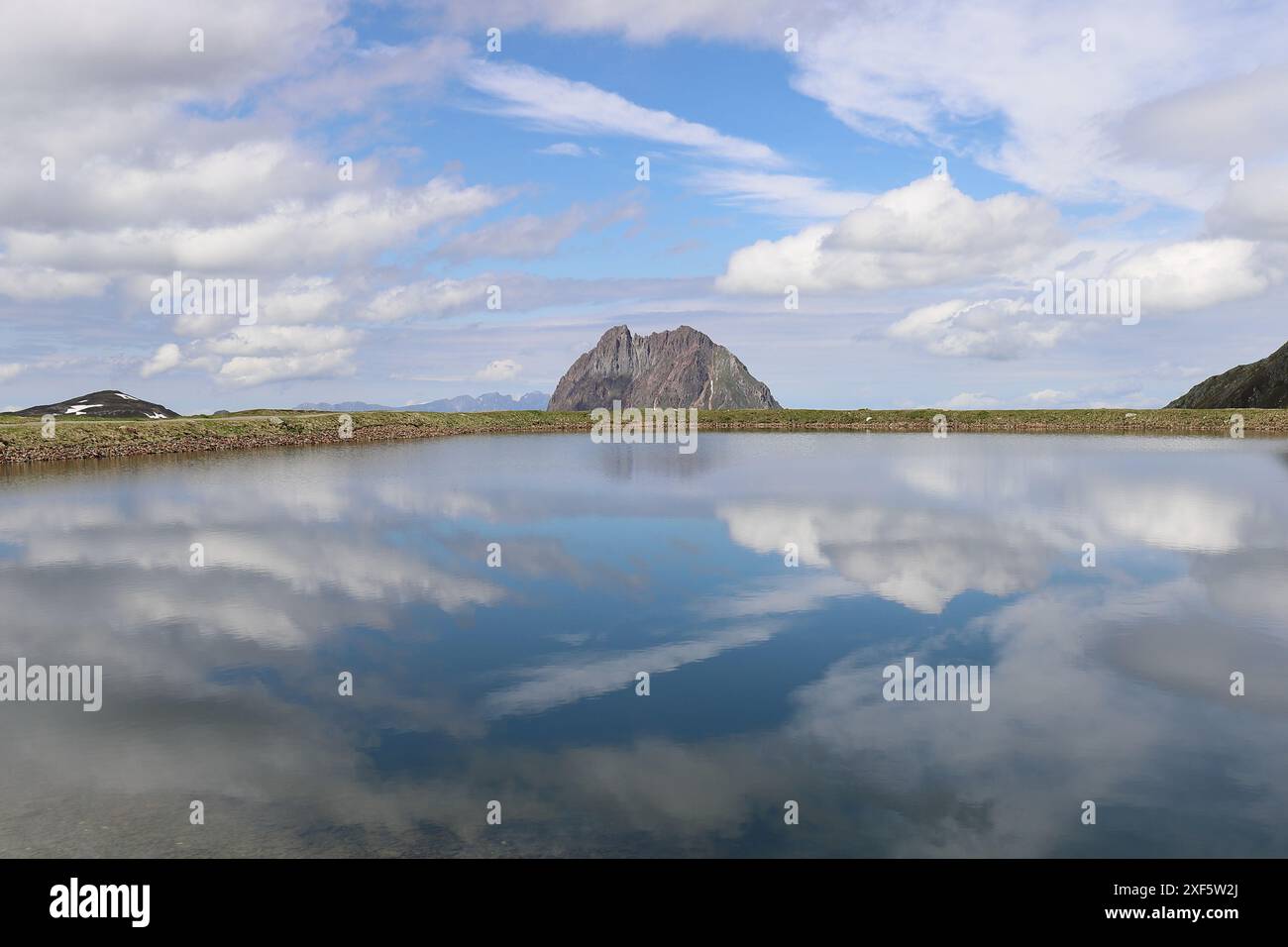 Vista di un bacino idrico sulla Wildkogel Arena, le cui acque blu riflettono nuvole bianche Foto Stock