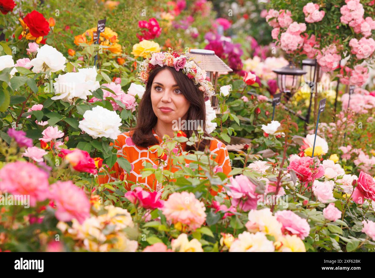 Londra, Regno Unito. 1 luglio 2024. Una donna posa tra le rose con una ghirlanda di fiori sulla testa. Giornata della stampa al RHS Hampton Court Flower Show. Crediti: Mark Thomas/Alamy Live News Foto Stock