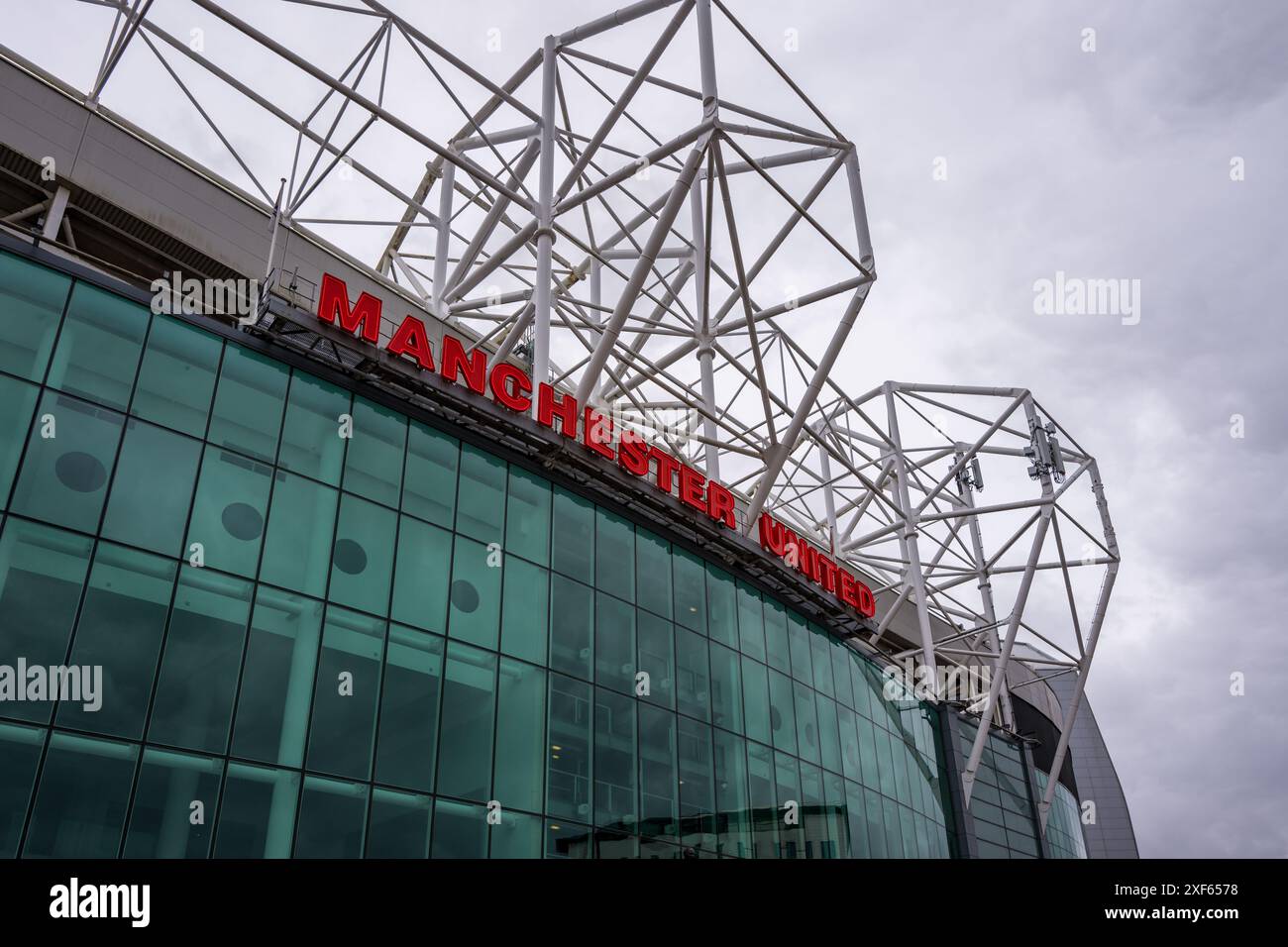 Manchester Trafford Regno Unito 29 giugno 2024. Vista esterna di uno stadio moderno con architettura suggestiva e audace cartellonistica sotto un cielo nuvoloso. Foto Stock