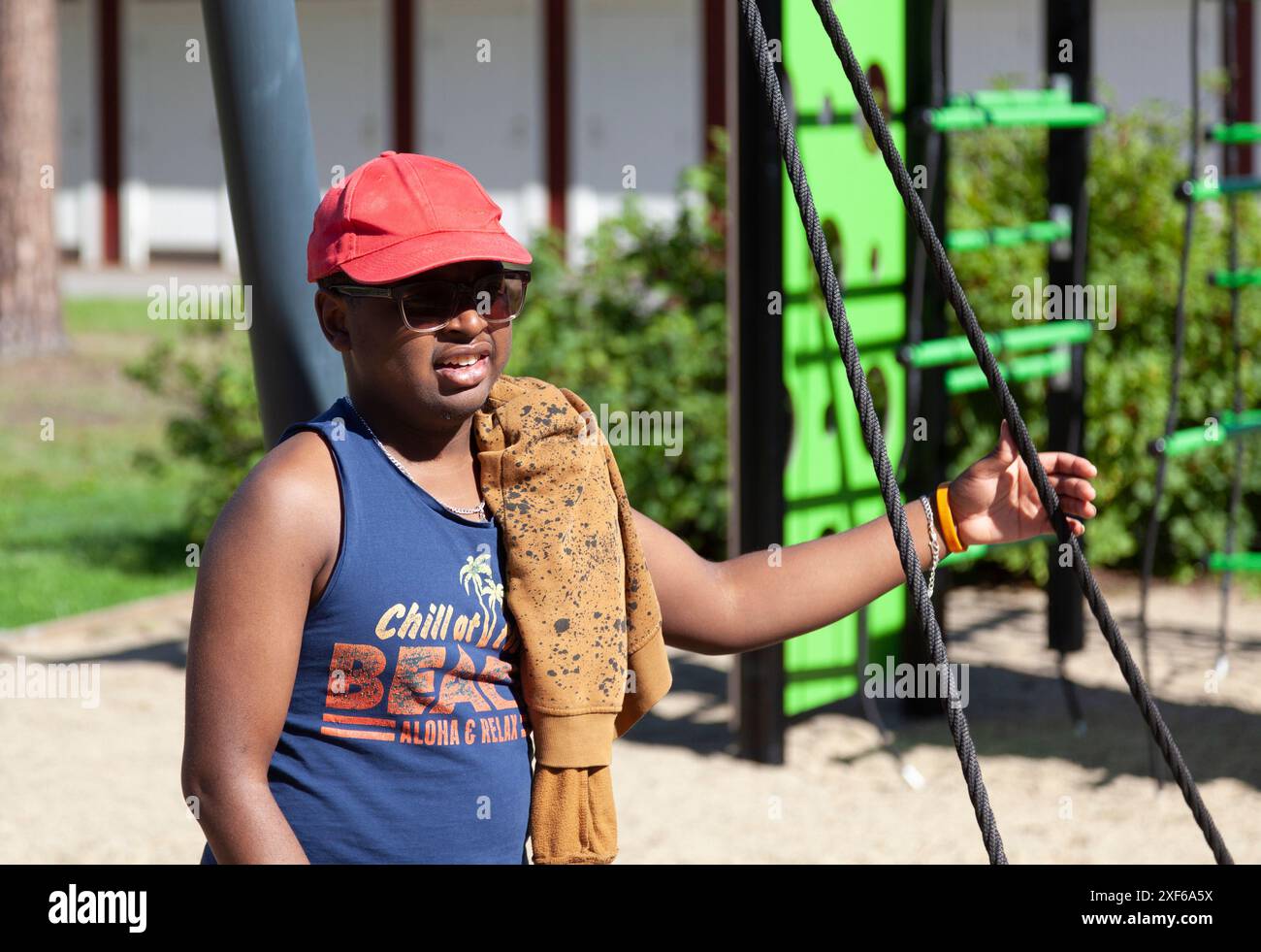 Uppsala, Svezia - 14 agosto 2023: Giovane con occhiali da sole e difficoltà mentali sul parco giochi Foto Stock