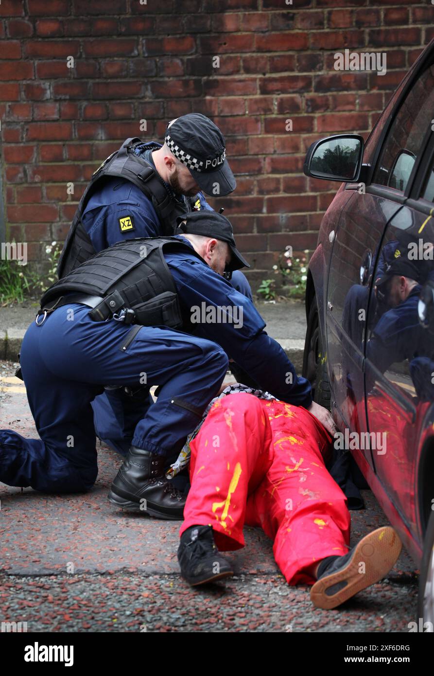 Manchester, Inghilterra, Regno Unito. 1 luglio 2024. Gli agenti di polizia ispezionano un attivista attaccato a un'auto e la loro serratura fuori dagli uffici della CDW. Palestine Action ha preso di mira direttamente le imprese di Elbit Systems, ma anche gli attivisti hanno preso di mira aziende partner della compagnia israeliana di armi e coloro che investono nella società. Cinque aziende nell'ultimo anno hanno interrotto tutti i legami con il produttore di armi dopo aver subito ripetute azioni dirette, tra cui la chiusura di uffici per mano dell'azione palestinese. CDW fornisce soluzioni IT per Elbit Systems. (Immagine di credito: © Martin Pope/ZU Foto Stock