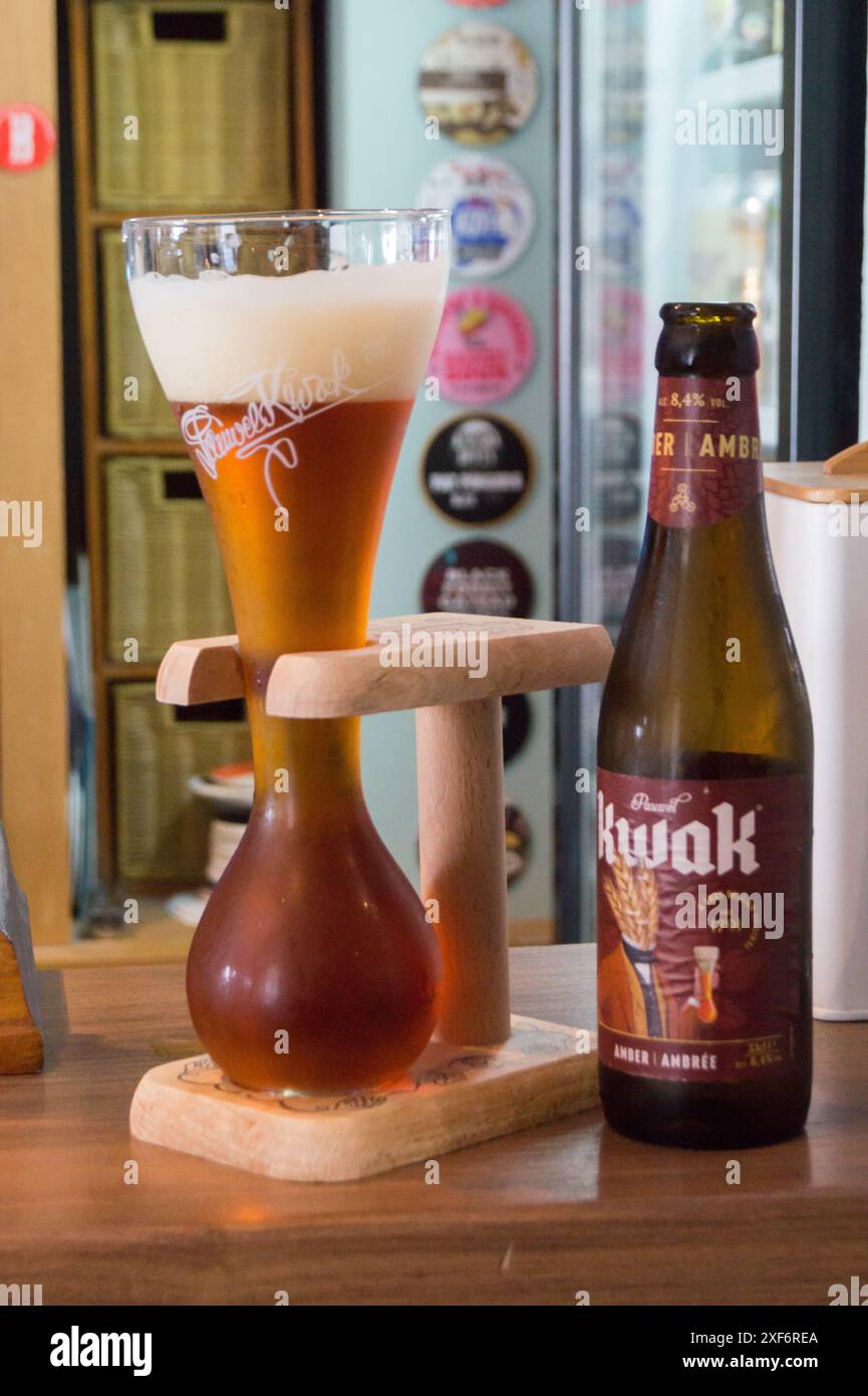 Una bottiglia e un bicchiere di birra belga Kwak nel suo stand in legno o "sabot" Foto Stock