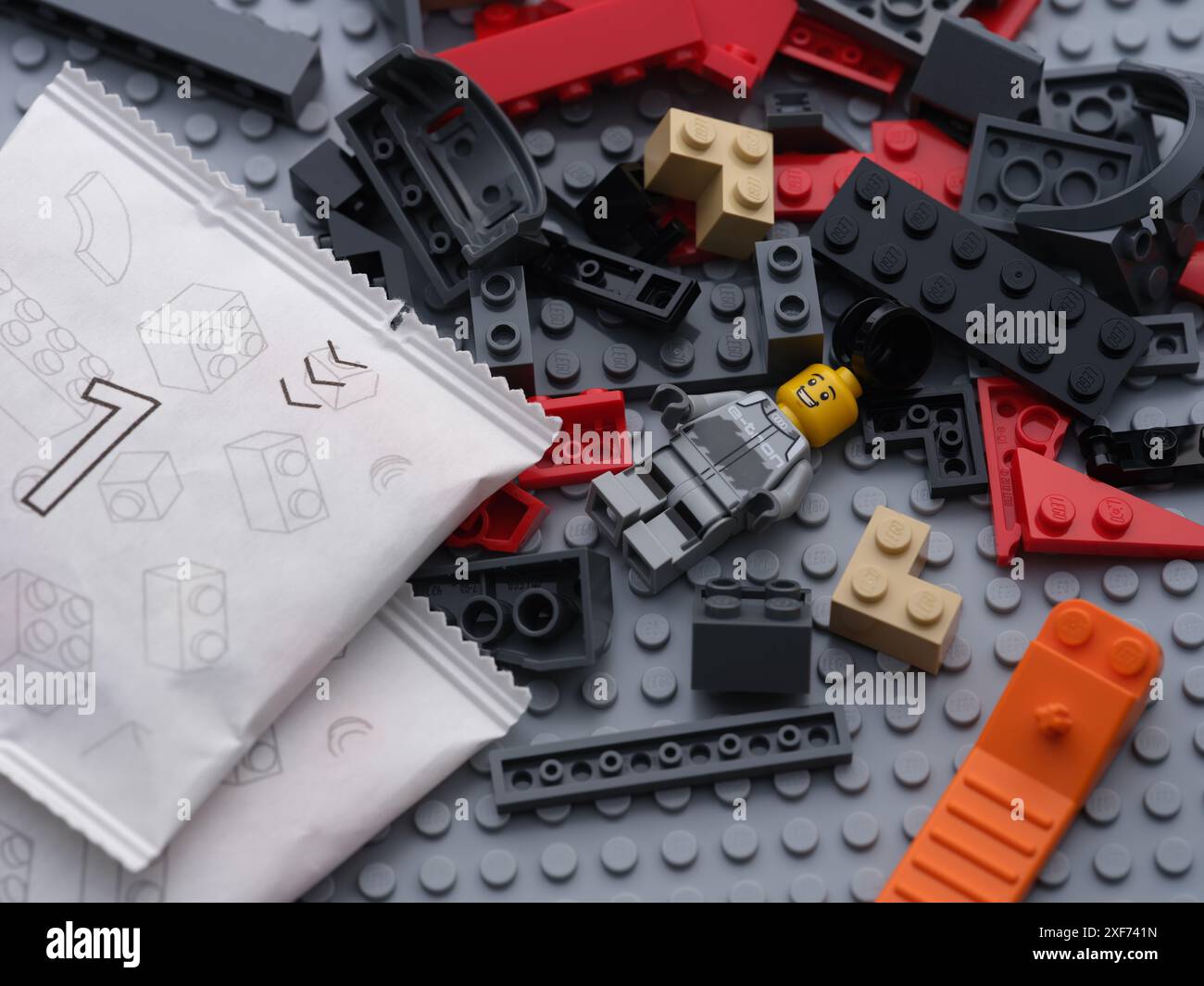 Tambov, Federazione Russa - 22 giugno 2024 blocchi Lego, pezzi, minifigure, separatore di mattoni e sacchetti di carta con pezzi Lego su una piastra di base grigia Foto Stock